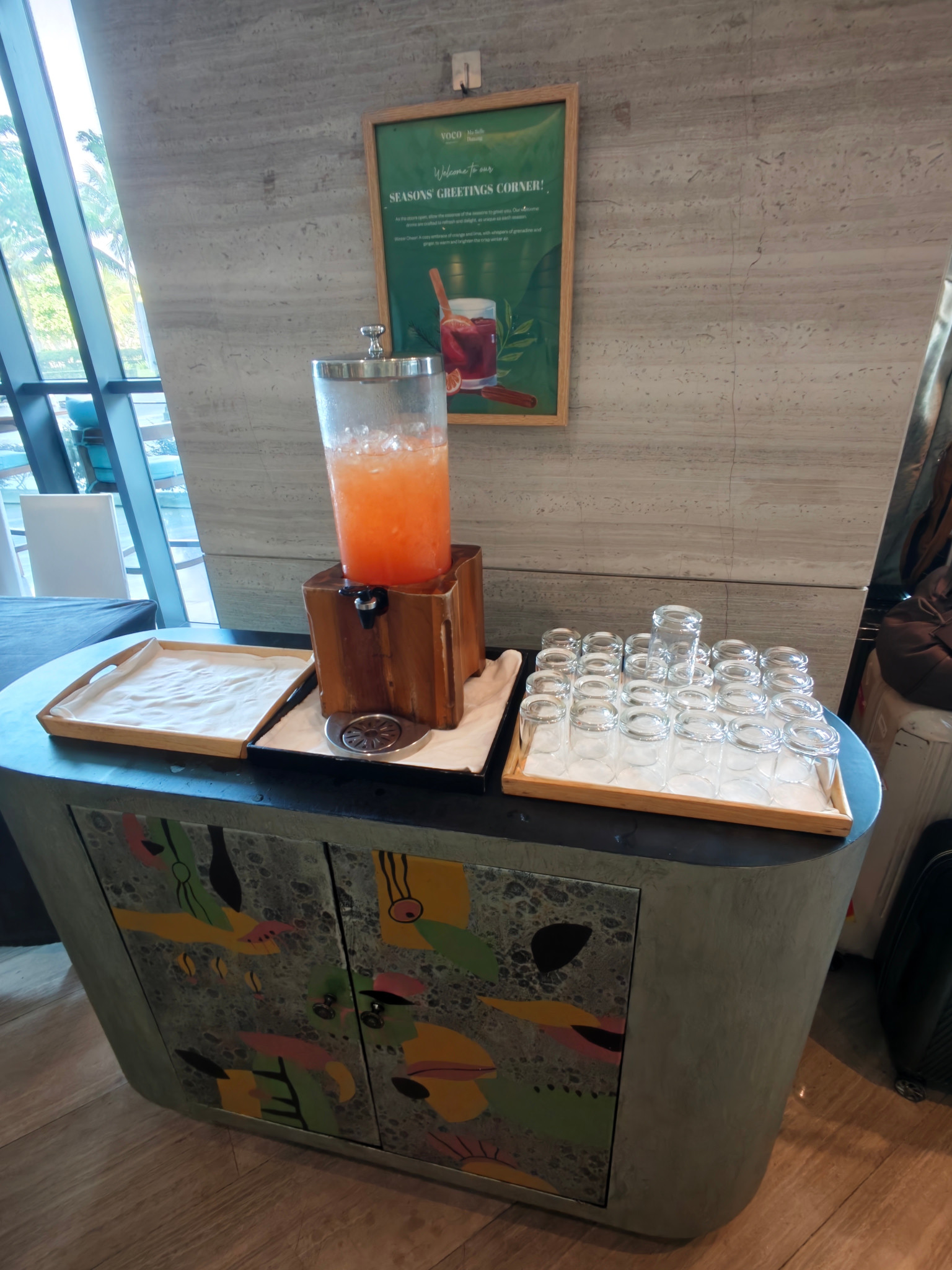 大廳的飲品台,玻璃杯與飲品容器排列在彩繪櫃上。